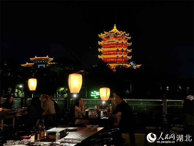游客登上天台，赏美景、品美食，沉浸式饱览黄鹤楼的璀璨夜景。人民网 彭昀迪摄